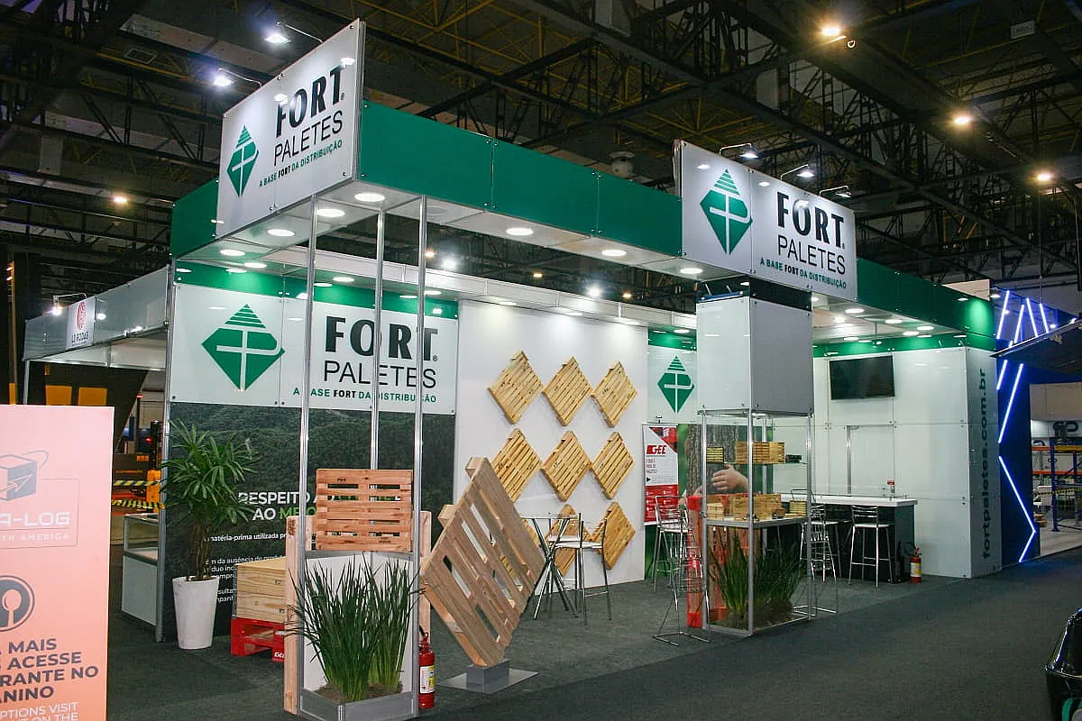 Stand padrão para feira com estrutura modular, testeiras verdes, painéis brancos, balcão e exposição de paletes.