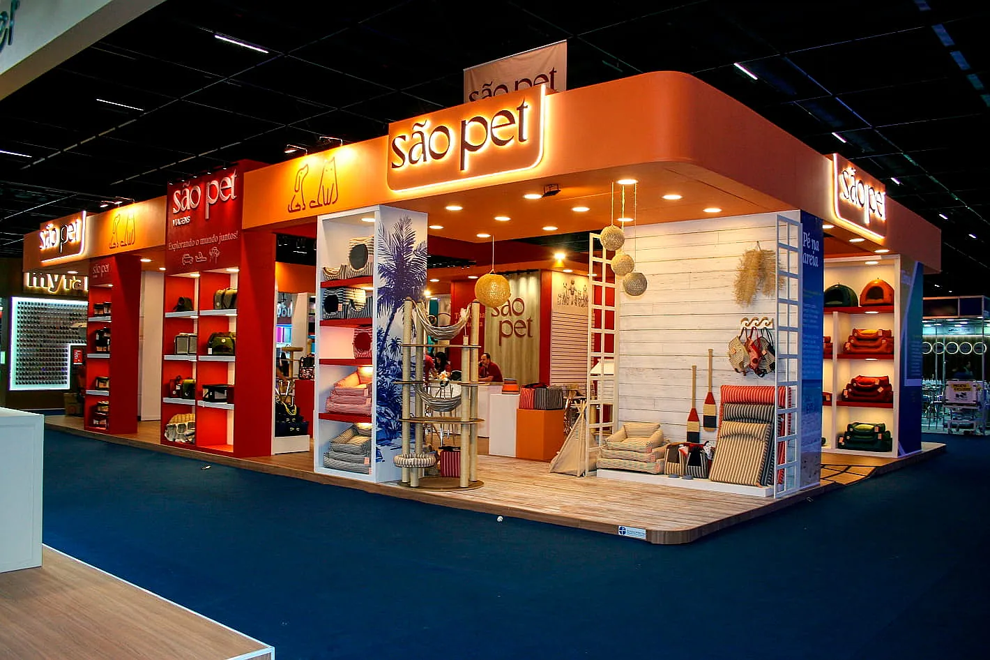Stand da São Pet, com testeira retroiluminada em laranja, piso de madeira e nichos de produtos para pets.