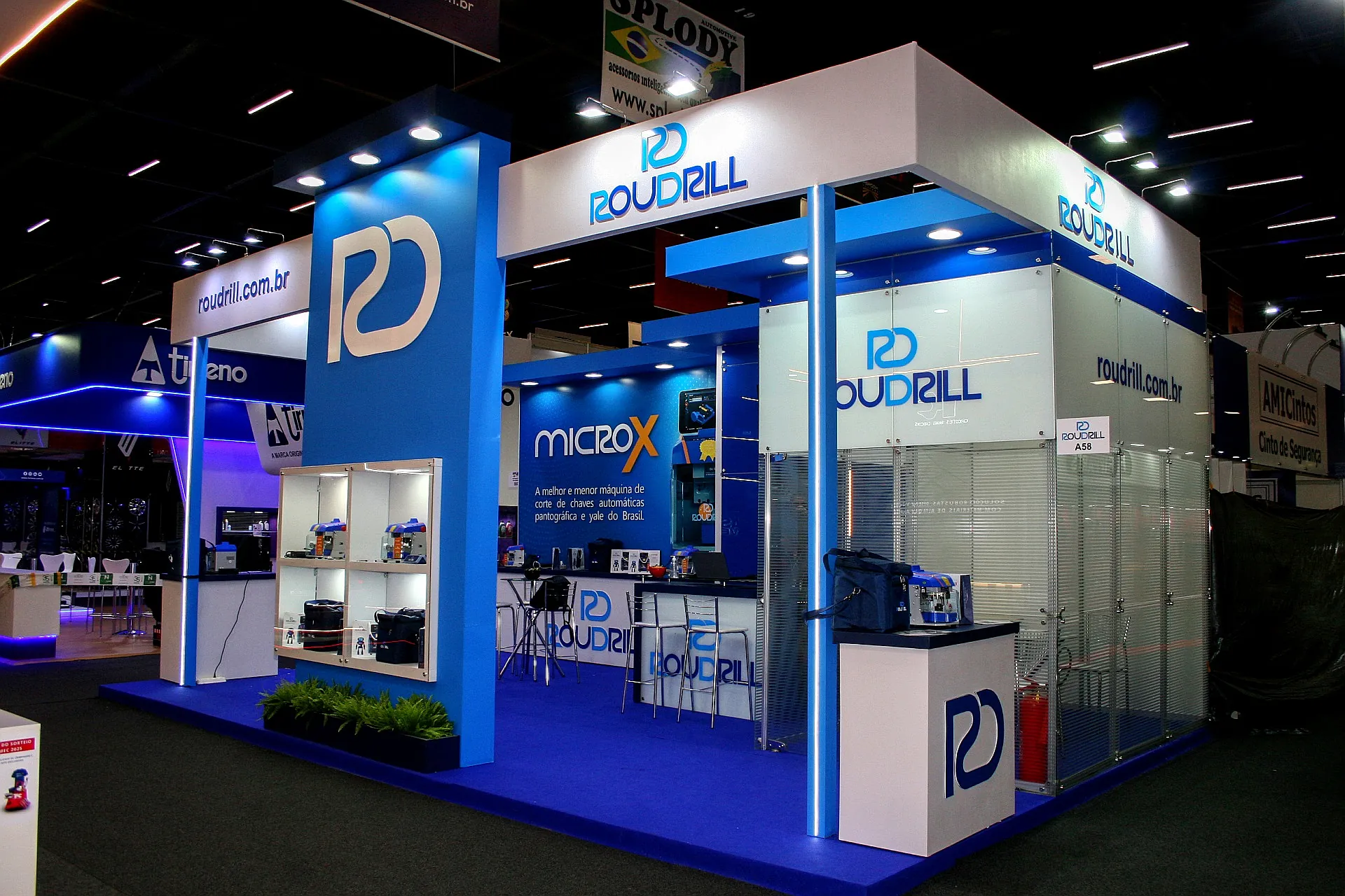 Stand da Roudrill na Automec, em azul e branco, com vitrine de máquinas, balcão de atendimento e fechamento em vidro.