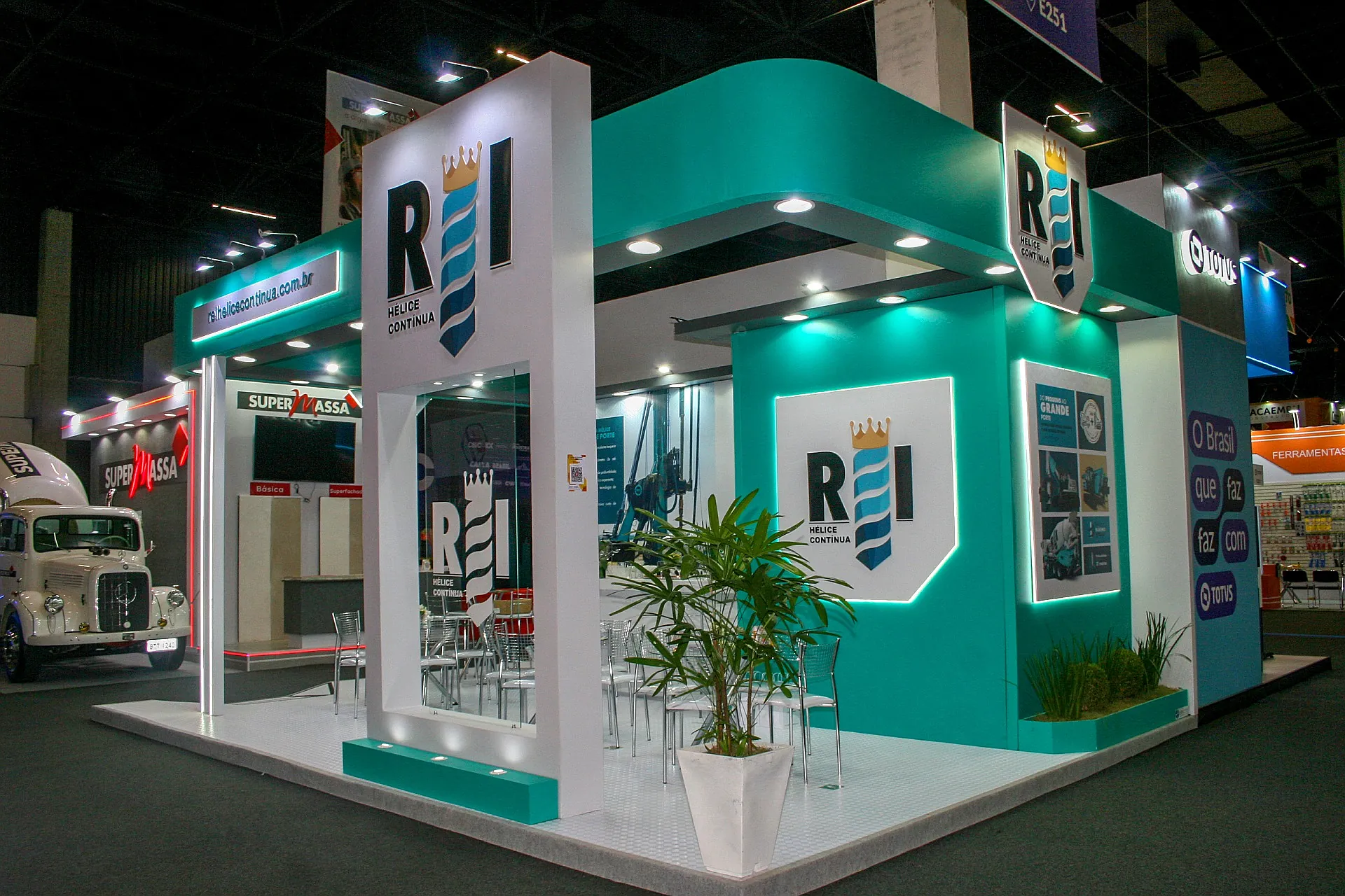 Stand da REI Hélice Contínua na Feicon 2025, em verde-água e branco, com logotipos retroiluminados e lounge de mesas altas.