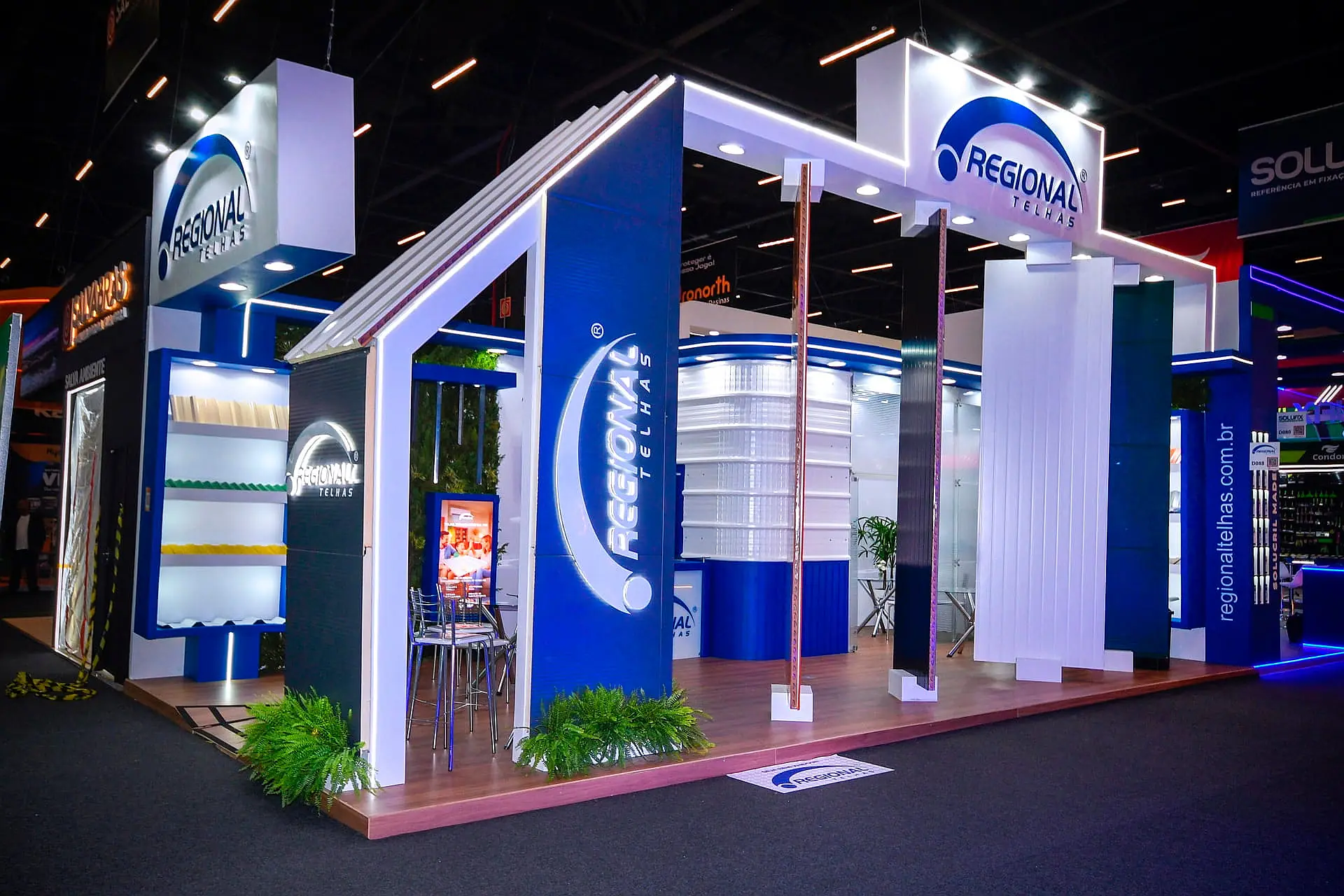 Stand construído com pórtico inclinado, piso elevado de madeira e paredes expositoras iluminadas na Feicon 2026.