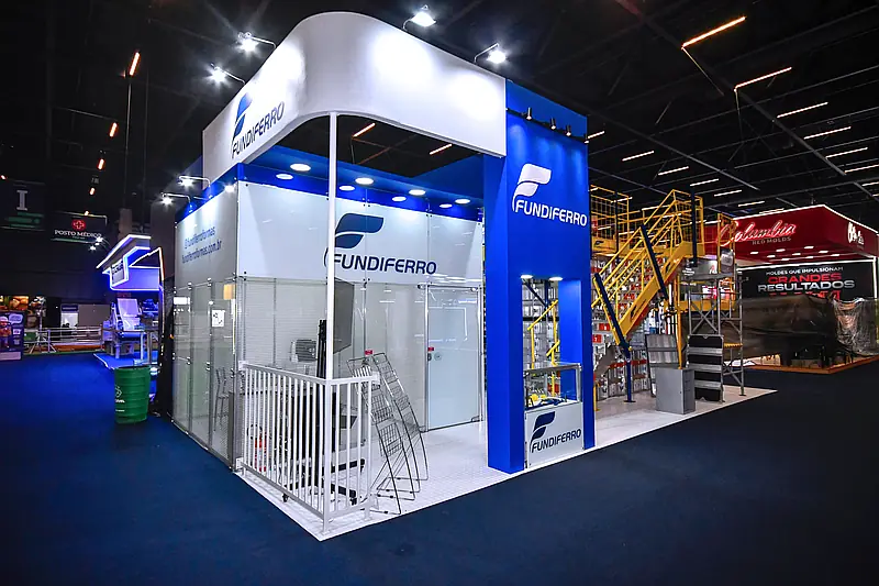 Stand misto azul com testeira curva construida em madeira e areas internas fechadas em estrutura modular e vidro.