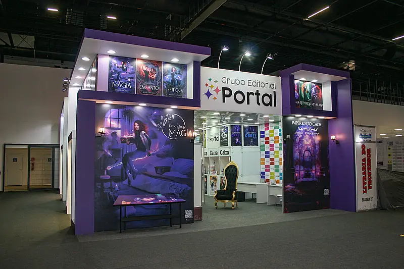 Stand misto com fachada roxa construída, displays iluminados de produtos e interior modular com balcões.
